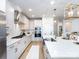 Bright kitchen features white cabinets, stainless steel appliances, and a large marble countertop island with a gold faucet at 527 Morrows Turnout Way, Pineville, NC 28134