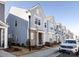 Street view showcasing a row of modern townhomes with light blue siding and stone accents, with sidewalks and landscaping at 527 Morrows Turnout Way, Pineville, NC 28134