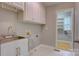 Functional laundry area with utility sink, white cabinets, and access to a storage space at 5306 Club View Dr, Concord, NC 28025