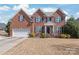 Charming red brick two-story home featuring a two-car garage, manicured lawn, and covered front entry at 5608 Old Town Ln, Gastonia, NC 28056
