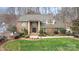 Charming two-story brick home with a lush green lawn, mature trees, and beautifully landscaped front yard at 8909 Abberley Ct, Huntersville, NC 28078