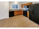 Kitchen with tile floors, wooden cabinets, black appliances, and a window over the sink at 10312 Hugue Way, Charlotte, NC 28214