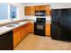 Well-lit kitchen with black appliances, tan countertops, and honey oak cabinetry at 10312 Hugue Way, Charlotte, NC 28214