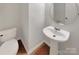 Simple powder room featuring pedestal sink, round mirror, and tiled flooring at 10312 Hugue Way, Charlotte, NC 28214