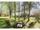 This backyard has mature trees, a green lawn, fire pit, and patio with the house in the background at 12421 Poplar Forest Dr, Charlotte, NC 28278