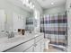 Well-lit bathroom featuring a double sink vanity, tiled floors, and a shower with a decorative shower curtain at 13923 Jacks Ln, Pineville, NC 28134