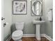 Chic half-bathroom with a modern pedestal sink, stylish fixtures, and artwork, complemented by wood-look flooring at 13923 Jacks Ln, Pineville, NC 28134