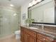 Updated bathroom with a glass shower, modern vanity, granite countertop and decorative mirror at 222 S Caldwell St # 1803, Charlotte, NC 28202