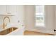 Bright laundry room with white cabinets, quartz countertops, gold hardware, and stainless steel sink at 2355 Emanuel Church Rd, Rockwell, NC 28138