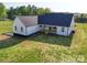 Backyard aerial view of a modern farmhouse featuring a dark roof, white siding, and a covered porch at 2355 Emanuel Church Rd, Rockwell, NC 28138