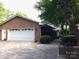 Side view of a brick home featuring an attached two-car garage with white doors at 2818 Cherry Ln, Denver, NC 28037