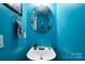 Cozy powder room with modern vanity and round mirror, painted in vibrant blue, offers a refreshing space at 4213 Devonbridge Ln, Charlotte, NC 28269