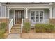 Inviting covered front porch with stone stairs, white railing and a decorative wood and glass front door at 5431 Meadowcroft Way, Fort Mill, SC 29708