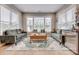 Sunlit living room featuring plush sofas, stylish rug, and a large window overlooking the front yard at 5431 Meadowcroft Way, Fort Mill, SC 29708