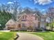 Elegant brick home with a three-car garage, a circular driveway, and manicured lawn on a sunny day at 5824 Preston Ln, Charlotte, NC 28270