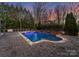 Backyard pool with stone waterfall feature surrounded by lush landscaping and stone pavers at 5824 Preston Ln, Charlotte, NC 28270