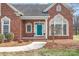 Close-up of brick house with blue door, portico entrance, and manicured landscaping at 7925 Tottenham Dr, Harrisburg, NC 28075