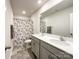 Bathroom featuring double sink vanity, large mirror, and tiled shower with decorative curtain at 9025 Remnick Dr, Gastonia, NC 28056