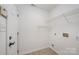 Tile flooring and storage shelves enhance a well-lit laundry room with door, ensuring organized and efficient utility at 10130 Illoria Dr, Charlotte, NC 28273