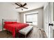 Cozy bedroom with a ceiling fan, window, wood-look floors and a comfortable bed with red linens at 10961 Carmel Crossing Rd, Charlotte, NC 28226