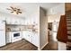 Bright kitchen with white cabinetry and appliances, adjacent to the living area and staircase at 10961 Carmel Crossing Rd, Charlotte, NC 28226