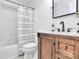 Bathroom with wooden vanity, modern black faucet, white countertop, toilet, and shower with black and white curtain at 13930 Thompson Rd, Mint Hill, NC 28227