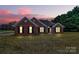 Charming single-story brick home featuring classic shutters and a well-manicured front lawn at dusk at 13930 Thompson Rd, Mint Hill, NC 28227