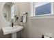 Stylish half-bathroom with a modern pedestal sink, round mirror, and natural light at 15212 Caspian Way, Charlotte, NC 28278