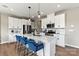 Bright kitchen features a center island with a sink, stainless steel appliances, white cabinets, and pendant lighting at 15212 Caspian Way, Charlotte, NC 28278