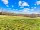 Vast grassy field with a small road, surrounded by trees and a clear blue sky with fluffy clouds at 164 Linderman Lake Ln, Kings Mountain, NC 28086