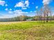 View of outbuilding on a grassy field with a road, trees and a clear blue sky with fluffy clouds at 164 Linderman Lake Ln, Kings Mountain, NC 28086