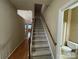 View of carpeted stairway with wood handrail, leading to the upper level, and nearby bathroom at 19915 Oak Leaf Cir, Cornelius, NC 28031