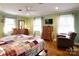 Cozy bedroom featuring hardwood floors, a colorful patchwork quilt, and a ceiling fan at 215 Biscoe Rd, Troy, NC 27371