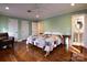 Bright bedroom with hardwood floors, patchwork quilt, and access to ensuite bathroom with pedestal sink at 215 Biscoe Rd, Troy, NC 27371