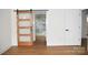 Bright, modern bedroom with light colored walls and wood-look floors features a sliding wooden door to the bathroom at 244 Stilwell Oaks Cir, Charlotte, NC 28212