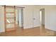 Bright bedroom with light colored walls and wood-look floors features a sliding wooden door to the bathroom and built-in shelving at 244 Stilwell Oaks Cir, Charlotte, NC 28212