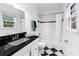 Updated bathroom with black granite countertop, tiled shower, and black and white tile floor at 4010 Hiddenbrook Dr, Charlotte, NC 28205