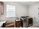 Modern laundry room with front load washer and dryer, tiled floor, window, and custom cabinet at 4922 Looking Glass Trl, Denver, NC 28037