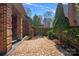 A brick patio with an arched gate is landscaped with lush trees and shrubbery at 7824 Hickory Stick Pl, Charlotte, NC 28277