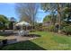 Lush green backyard with a patio set under an umbrella, trees, and swing at 7824 Hickory Stick Pl, Charlotte, NC 28277