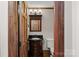 A charming half-bathroom with decorative mirror, unique vanity, dark granite top, and wooden accents at 7824 Hickory Stick Pl, Charlotte, NC 28277