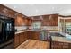 The U-shaped kitchen features stainless steel appliances, granite countertops, wood cabinets, and hardwood floors at 7824 Hickory Stick Pl, Charlotte, NC 28277