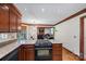 Open kitchen with wood cabinets, granite countertops, and stainless steel appliances, leading to a cozy living area at 7824 Hickory Stick Pl, Charlotte, NC 28277