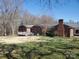 Brick home's backyard featuring a deck and lush greenery with trees and grass at 10843 Caroline Acres Rd, Fort Mill, SC 29707