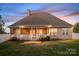 Backyard dusk view with covered porch, white railing, neutral siding, and lush green grass at 121 Dabbling Duck Cir, Mooresville, NC 28117