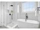Bright bathroom featuring walk-in shower, soaking tub, subway tile, and black fixtures at 121 Dabbling Duck Cir, Mooresville, NC 28117