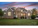 Stunning brick home with turret, manicured lawn, and professional landscaping at sunset at 121 Dabbling Duck Cir, Mooresville, NC 28117