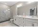 Contemporary bathroom with double vanity, framed mirrors, sleek tile, and walk-in shower with a built-in bench at 12312 Landry Renee Pl # 35, Charlotte, NC 28277