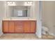 Bathroom featuring double sinks, wood cabinets, tile floors, and a large mirror at 12724 Hunting Birds Ln, Charlotte, NC 28278