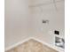 Small laundry room featuring tile floors, a wire shelf, and connections for a washer and dryer at 12724 Hunting Birds Ln, Charlotte, NC 28278